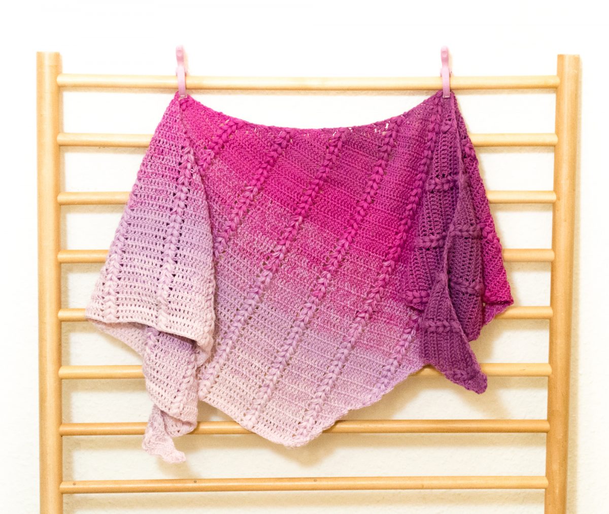 Pink to white gradient shawl draped over a wood grate